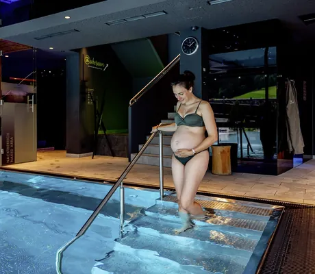 schwangere Frau im Bikini geht die Pooltreppe in der Riederalm hinunter