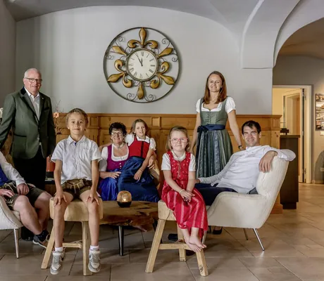 Inhaberfamilie Herbst aus der Riederalm sitzt in der Lobby vor der großen golden Uhr