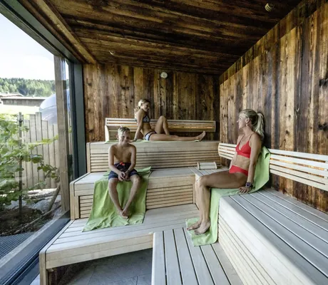 Frau mit zwei jugendlichen Kindern sitzt in der Familiensauna der Riederalm