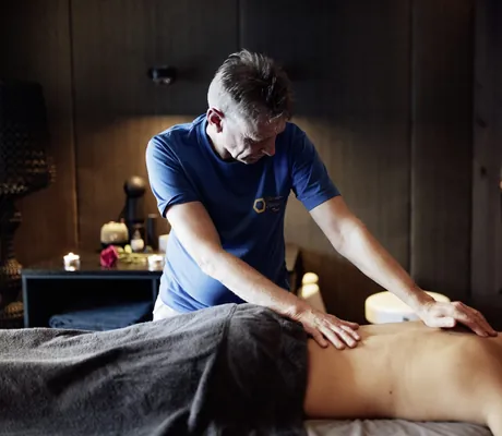 Mann in blauem Shirt massiert in der Riederalm eine blonde Frau