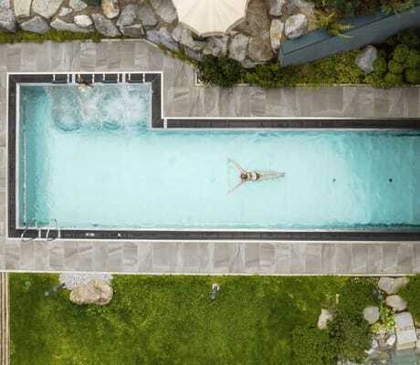 Blick von oben auf eine schwimmende Frau im Thermalwasserpool der Riederalm