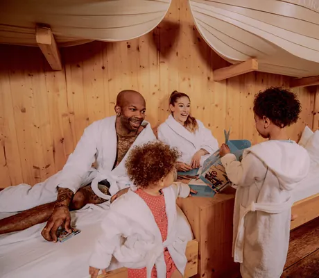 junge Familie mit zwei kleinen Kindern in Bademänteln in einem der Zimmer des Hotel Victory Therme Erding mit Betten in Schiffsform