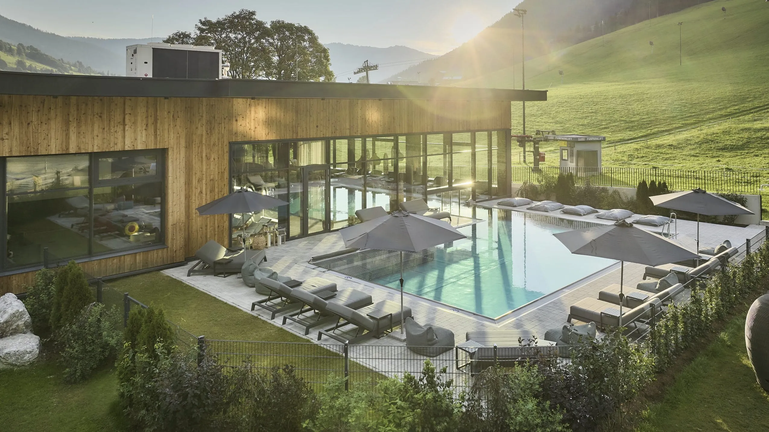 Blick auf den Au&szlig;enpool des Bauernhof Hotels Oberschwarzach, einem Familienhotel in &Ouml;sterreich, mit grauen Liegen am Rand