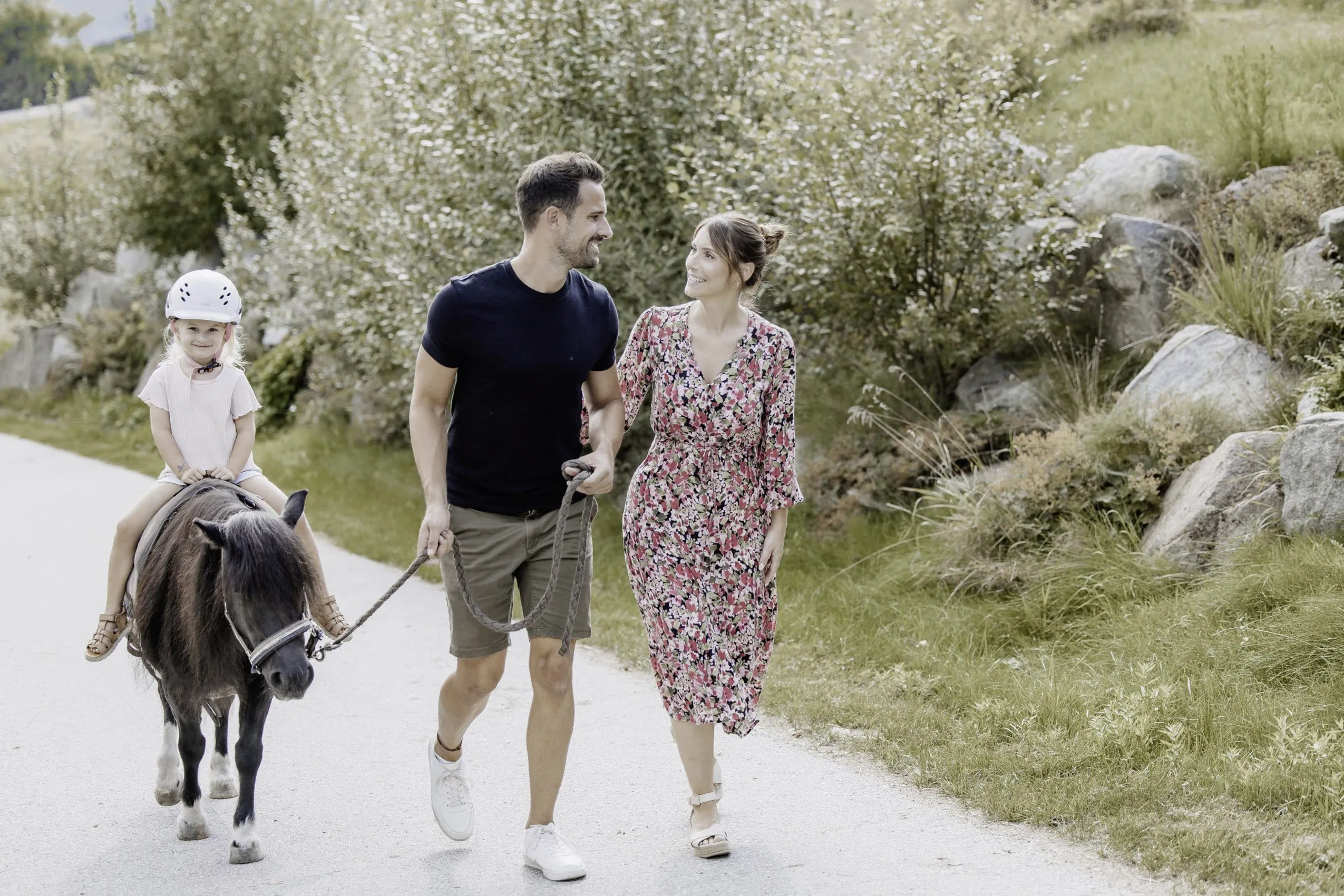 Pärchen macht Ponyspaziergang mit blondem Mädchen in der Nähe des Familotel Schreinerhof