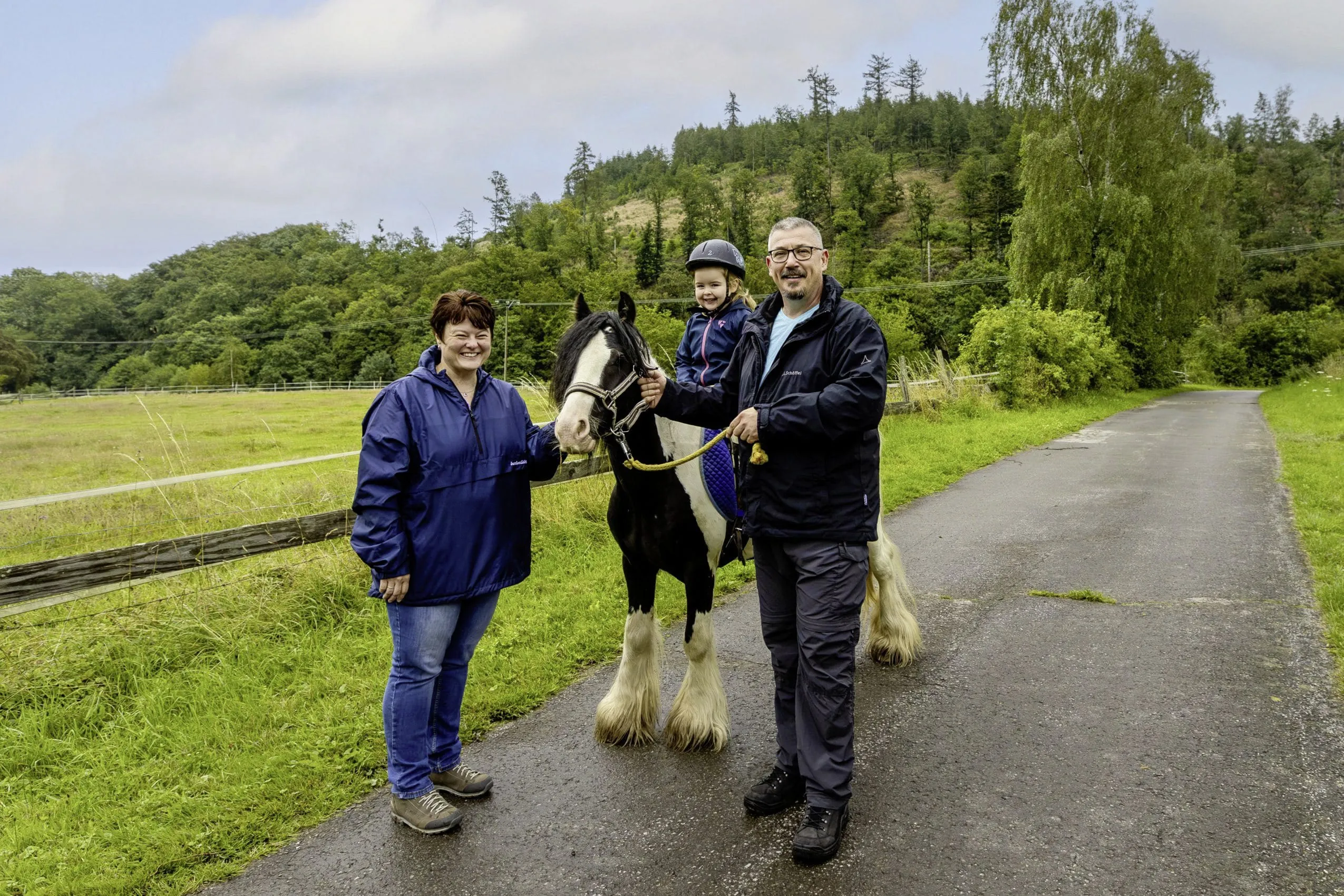 junges M&auml;dchen sitzt auf einem Pferd des Familotel Ottonenhof und wird von zwei Erwachsenen begleitet