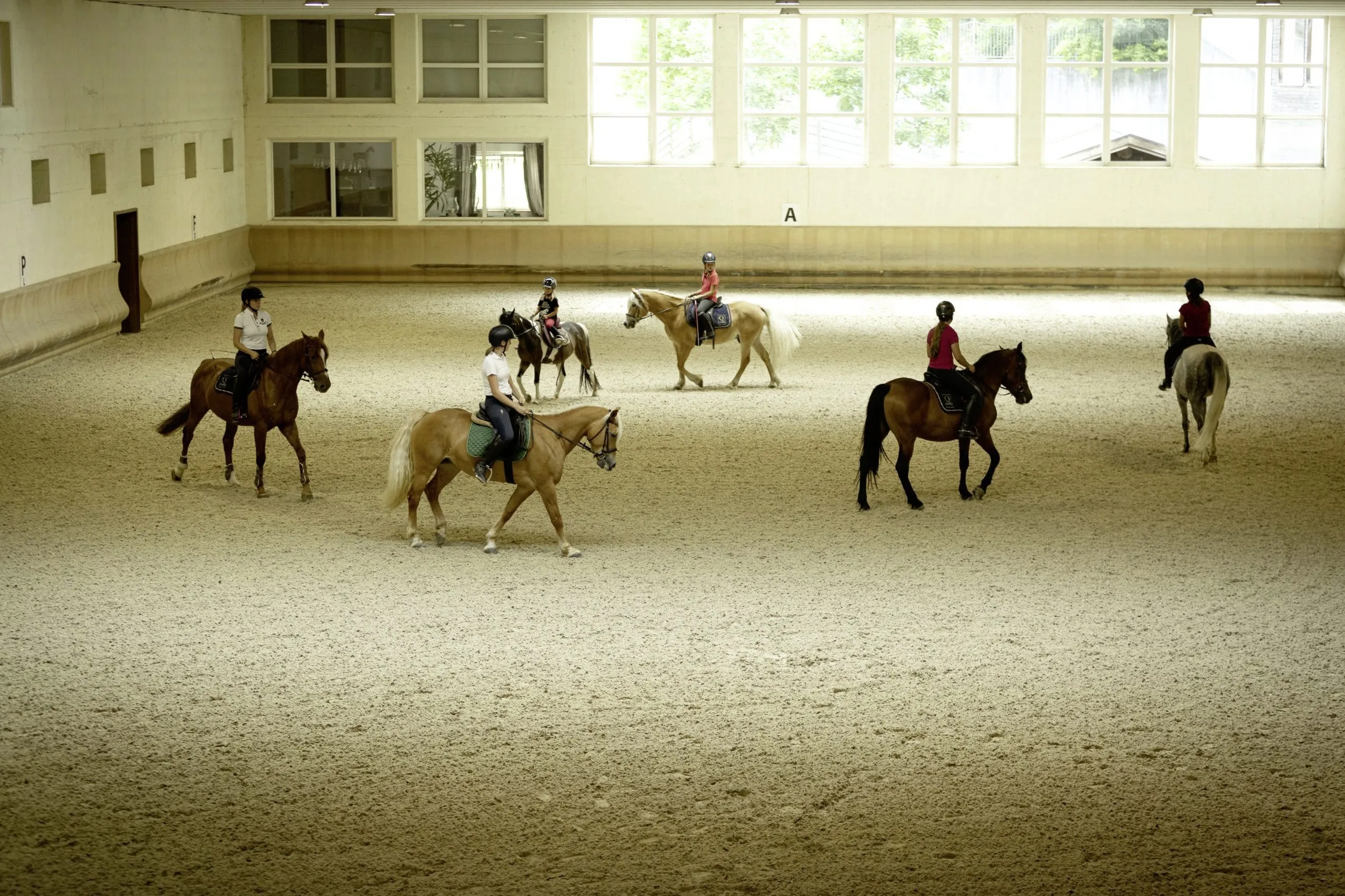 mehrere Reiter in der Reithalle des Quellenhof Luxury Resort Passeier