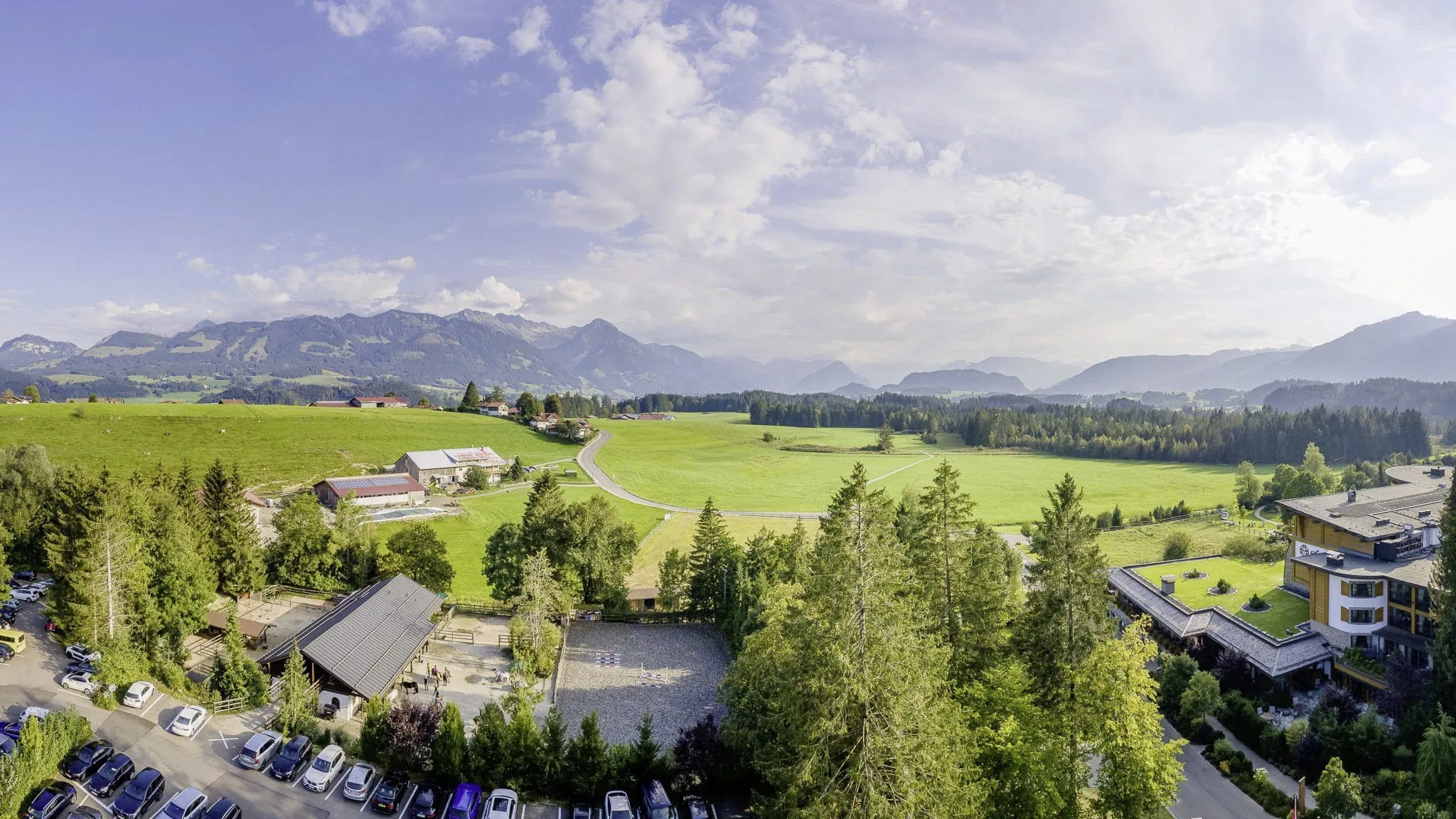Blick von oben auf den Reiterhof des Sonnenalp Resorts mit Bergpanorama im Hintergrund