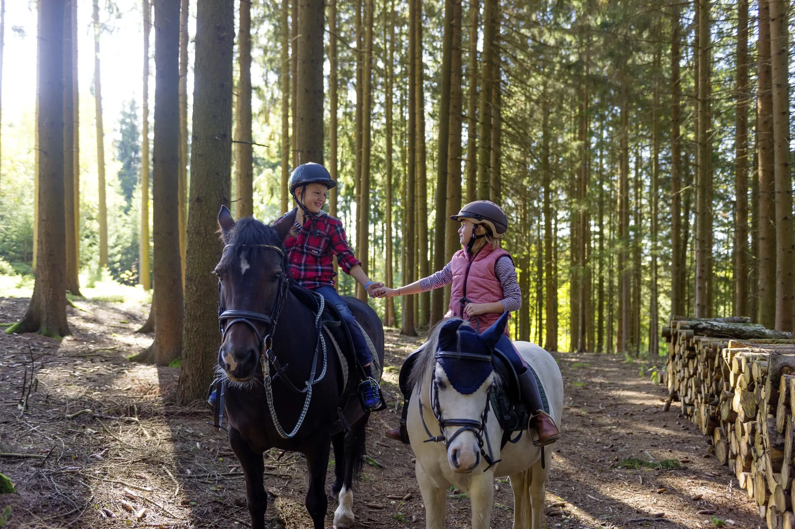 Junge und M&auml;dchen machen einen Ausritt im Wald in der N&auml;he des Ulrichshof und halten H&auml;ndchen