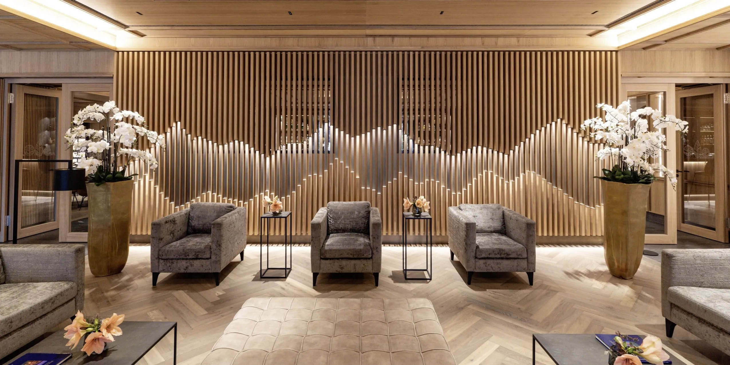 Lobby im Parkhotel Egerner H&ouml;fe mit Holzverstrebungen und gro&szlig;en Vasen mit Orchideen