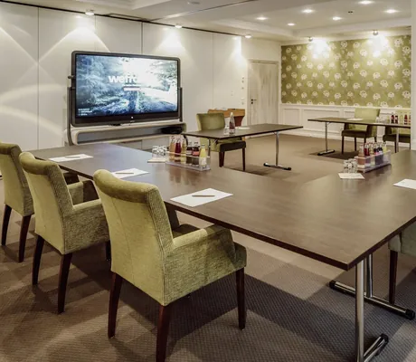 U-Form-Tagungsraum mit grünen Stühlen rund um Weframe-Monitor im Hotel Der Eisvogel