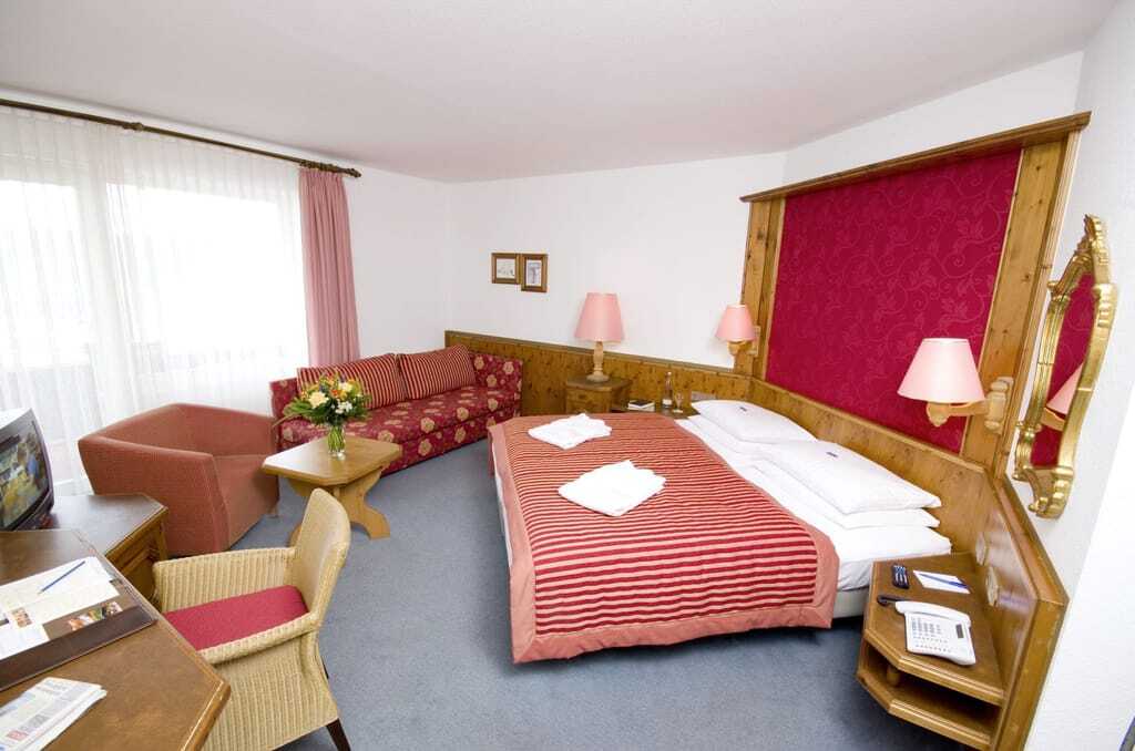 Dopplezimmer im Göbel's Hotel Rodenberg mit gestreifter Tagesdecke und roter Bettrückwand