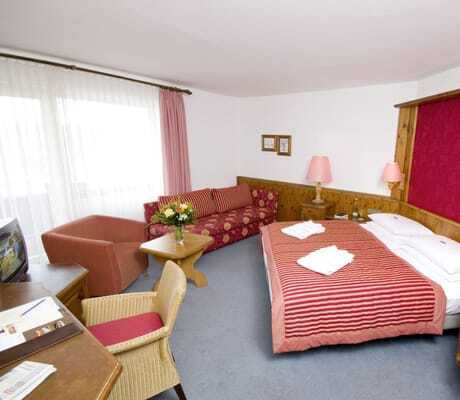 Dopplezimmer im Göbel's Hotel Rodenberg mit gestreifter Tagesdecke und roter Bettrückwand