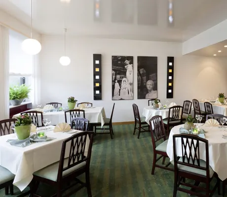 Restaurant im Kress Hotel mit grünem Teppich und schwarz-weißen Fotografien an der Wand