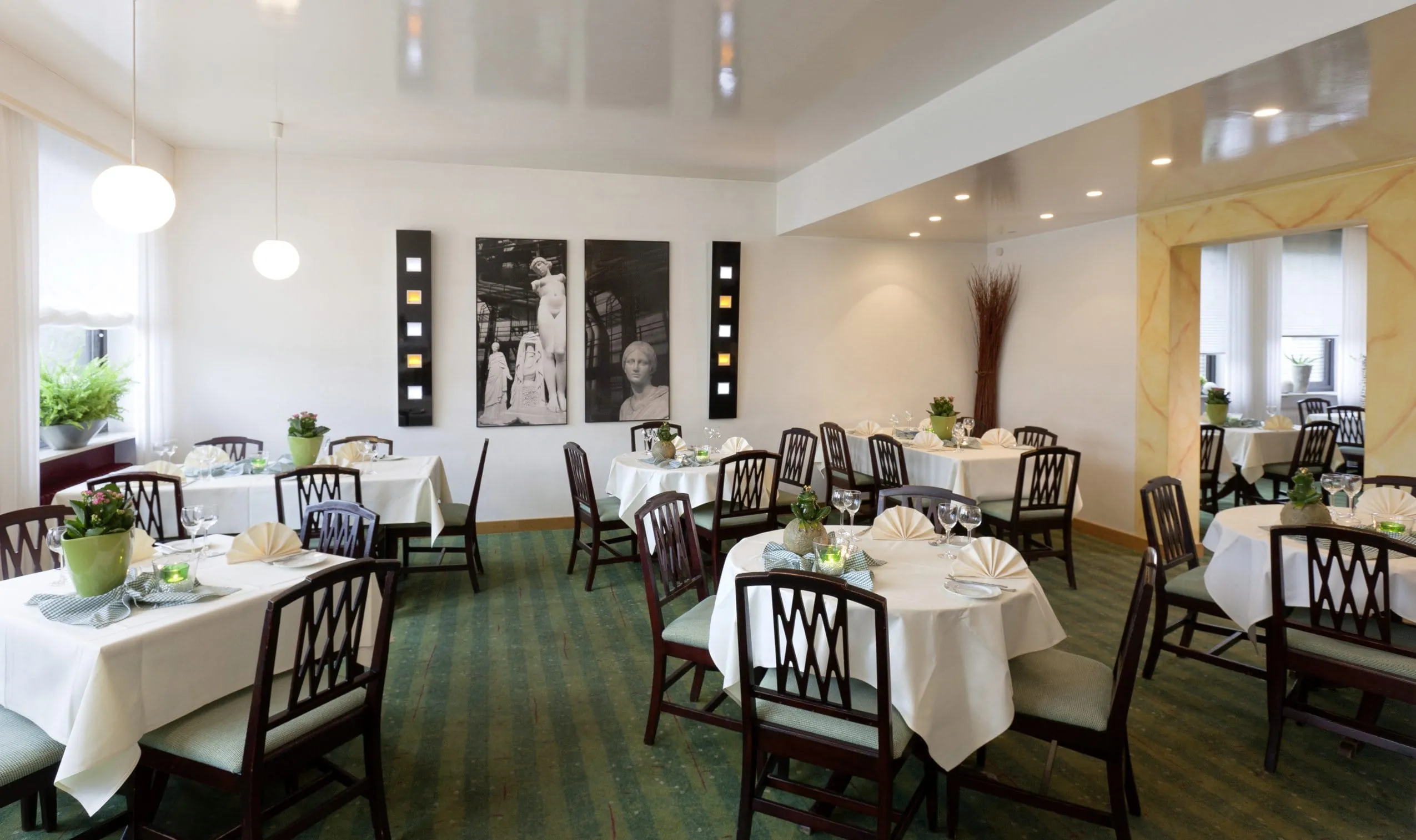 Restaurant im Kress Hotel mit gr&uuml;nem Teppich und schwarz-wei&szlig;en Fotografien an der Wand