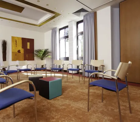 Stuhlkreis mit blauen Stühlen und rotem Teppich im Kress Hotel