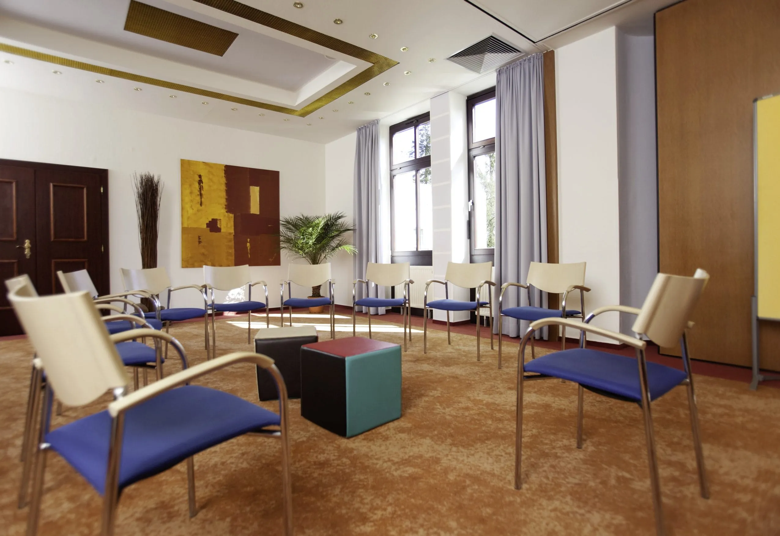 Stuhlkreis mit blauen St&uuml;hlen und rotem Teppich im Kress Hotel