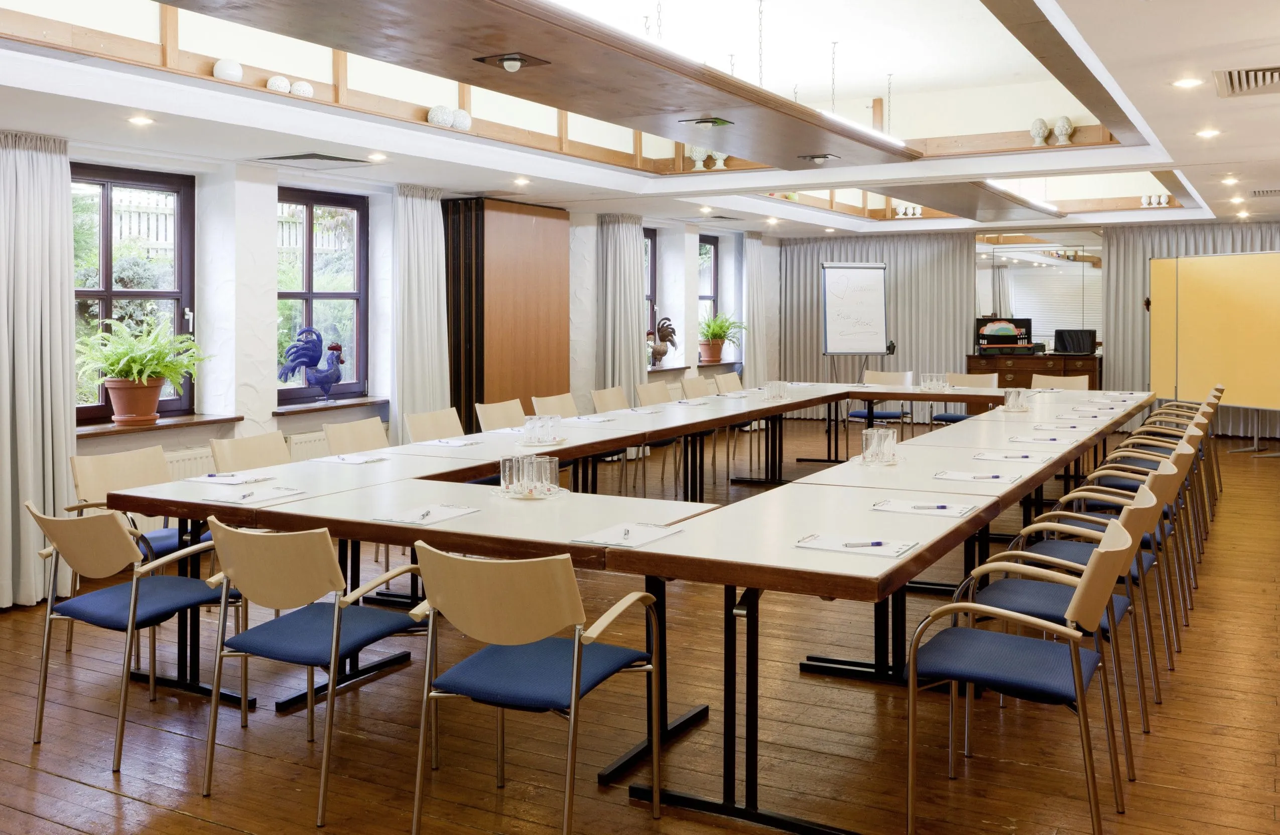 Tagungsraum im Kress Hotel mit blauen St&uuml;hlen und Hahn auf der Fensterank