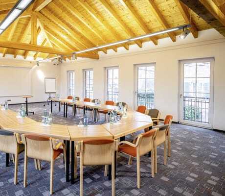 Tagungsraum unter dem Holzdach im Hotel Lamm mit dunkelblauem Teppich und U-Form-Bestuhlung