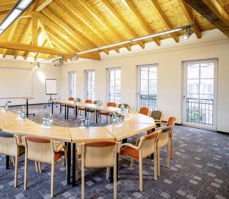 Tagungsraum unter dem Holzdach im Hotel Lamm mit dunkelblauem Teppich und U-Form-Bestuhlung