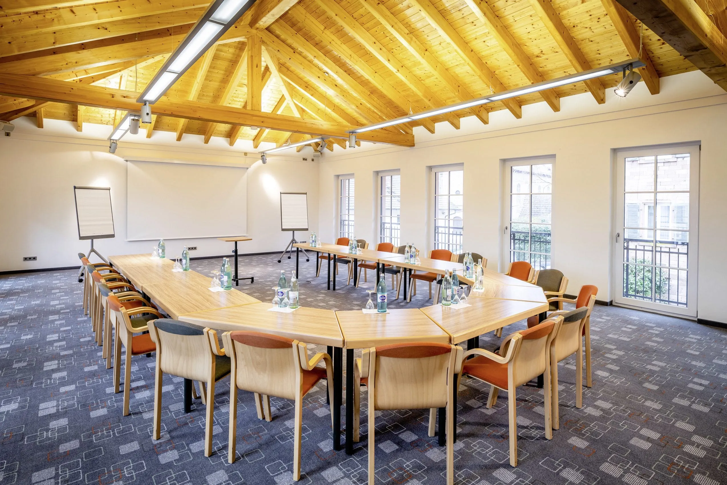 Tagungsraum unter dem Holzdach im Hotel Lamm mit dunkelblauem Teppich und U-Form-Bestuhlung