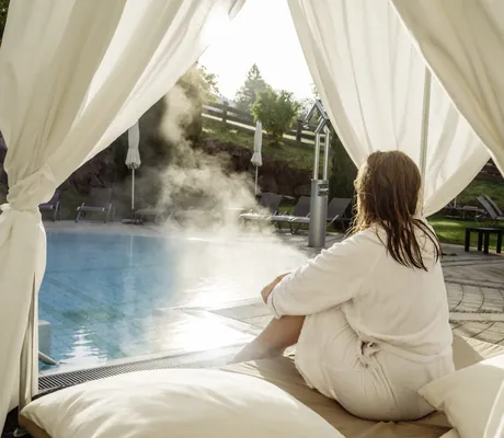 Frau in weißem Bademantel sitzt auf Daybed im A-Rosa Kitzbühel