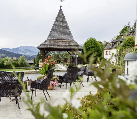 Terrasse im A-ROSA Kitzbühel mit Korbmöbeln und Schindeldach-Turm