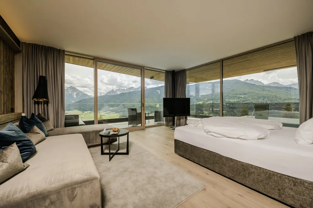 Zimmer im Alpen Tesitin mit naturfarbenen Couches und Balkonblick auf die Berge