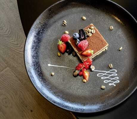 Tiramisu mit Beeren auf schwarzem Teller im Das Stemp