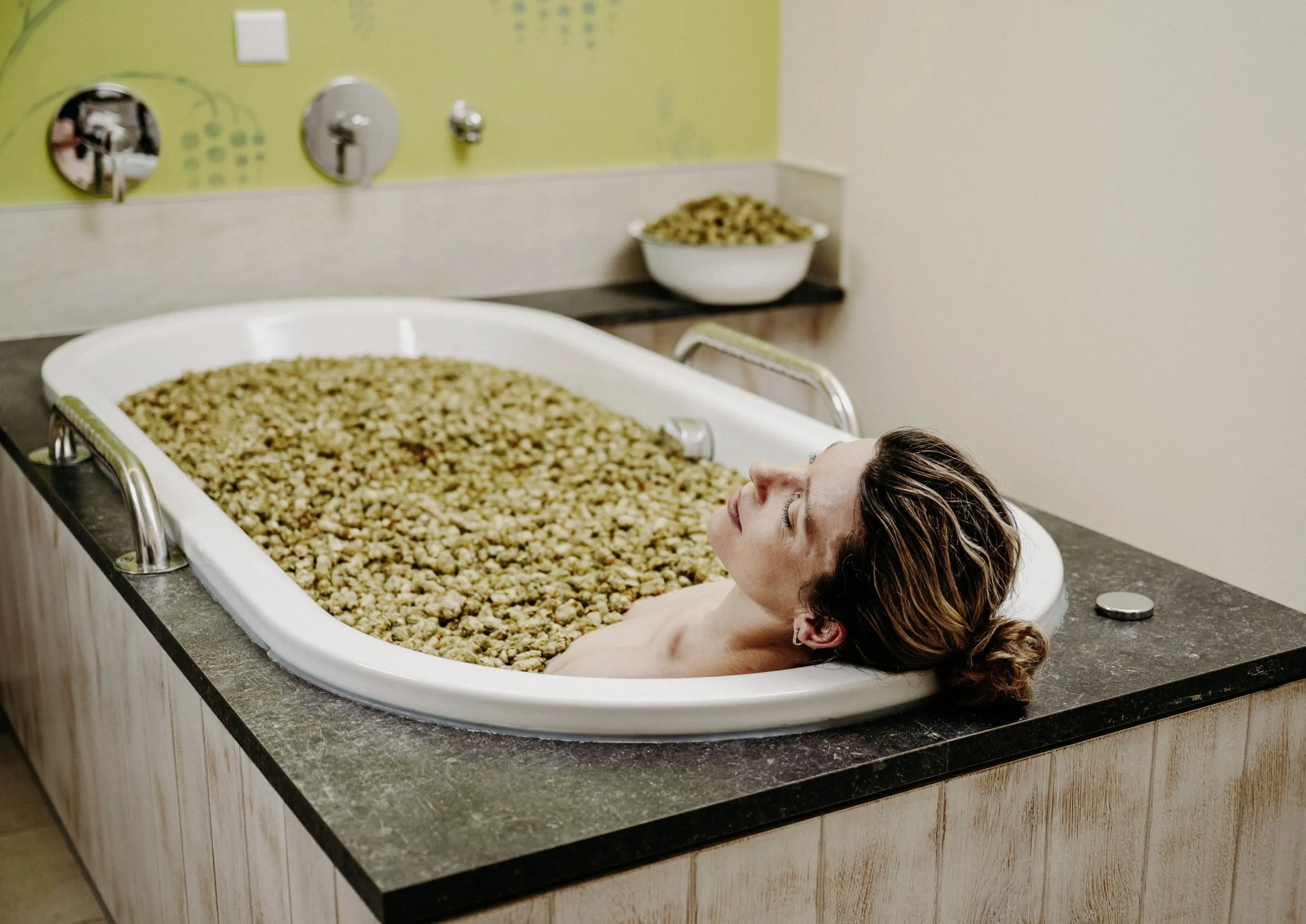 Frau liegt in Badewanne mit Hopfenbl&uuml;ten im Hotel Der Eisvogel