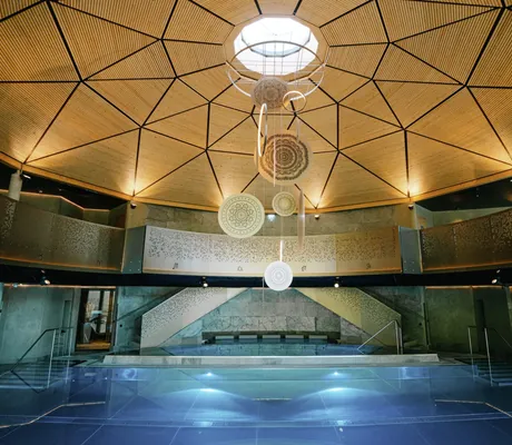 Indoorpool im Moutain Resort Feuerberg mit goldener Decke und goldenen Hänge-Ornamenten