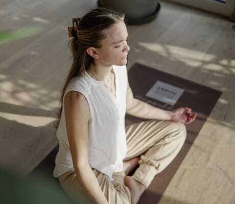 junge Frau meditiert auf einer Yogamatte im Panoramahotel Oberjoch
