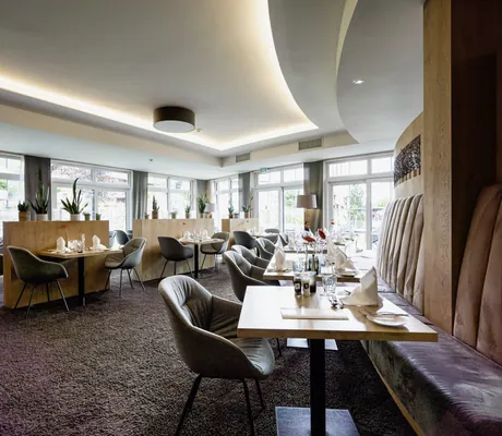 Restaurant mit grauen Polsterstühlen und rosa gepolsterten Sitzbänken im Panoramahotel Oberjoch