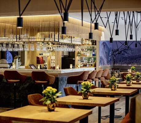 Bar im Pfalzblick Waldspa Resort mit hohen Barhockern in Rostrot und schwarzen Hängeleuchten