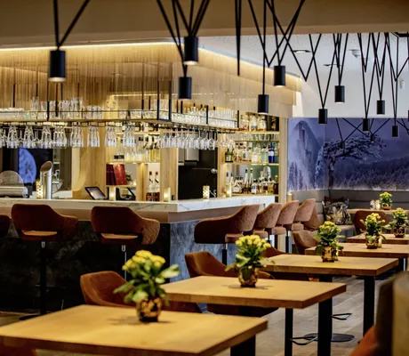 Bar im Pfalzblick Waldspa Resort mit hohen Barhockern in Rostrot und schwarzen Hängeleuchten