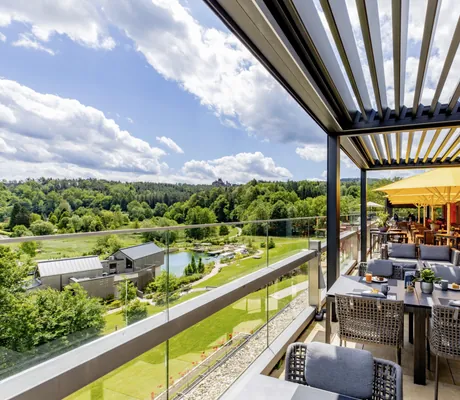überdachte Außenterrasse im Pfalzblick Waldspa Resort mit Blick auf den Naturbadeteich