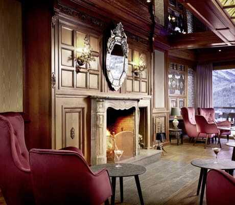 Lobby mit Holzvertäfelung und roten Hochlehner-Sesseln vor dem Kamin im Hotel Prinz-Luitpold-Bad