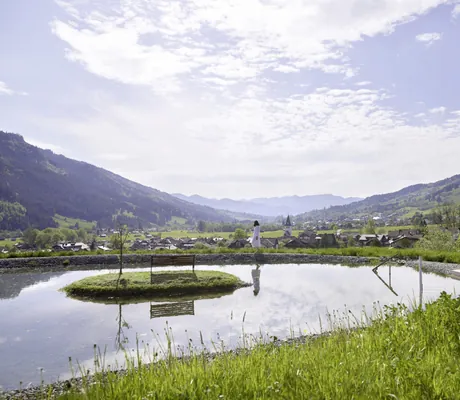 dunkelhaarige Frau im Bademantel steht am Naturteich des Hotel Prinz-Luitpold-Bad