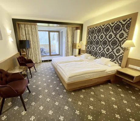 Zimmer im Hotel Prinz-Luitpold-Bad mit Teppich mit Lilienmuster und floraler Bettrückwand