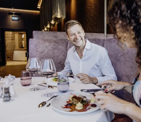 Paar sitzt am Tisch und genießt das Dinner mit Rotwein in der Riederalm