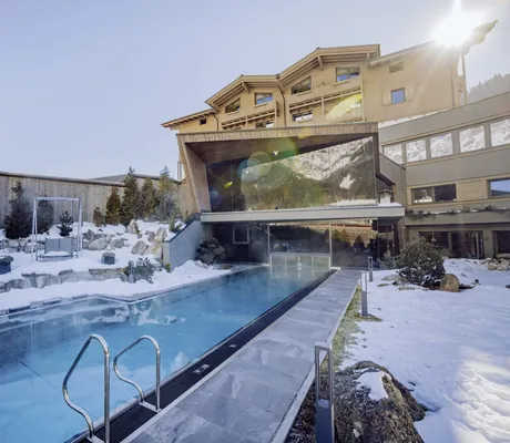 Thernalpool im Winter mit Blick auf das moderne Spagebäude der Riederalm