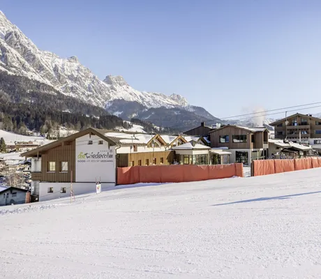 Frau in blauer Skijacke wedelt mit Skiern an der Riederalm vorbei