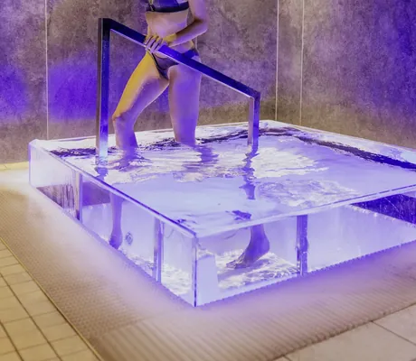 dunkelhaarige Frau in braunem Bikini steigt aus dem Tauchbecken in der Riederalm