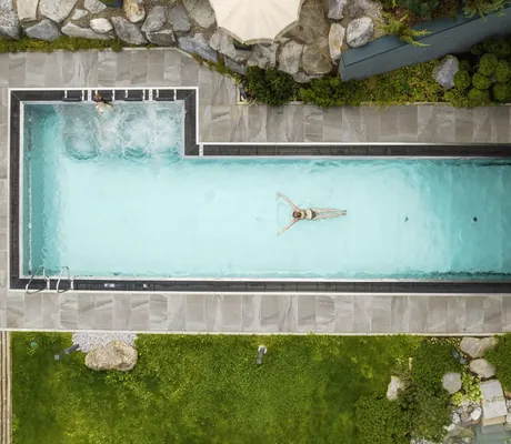 Drohnenansicht einer schwimmenden Frau im Thermalwasserpool der Riederalm