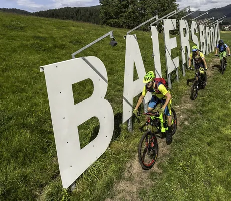 Biker fahren auf einem Trail entlang der großer Buchstaben der Stadt Baiersbronn
