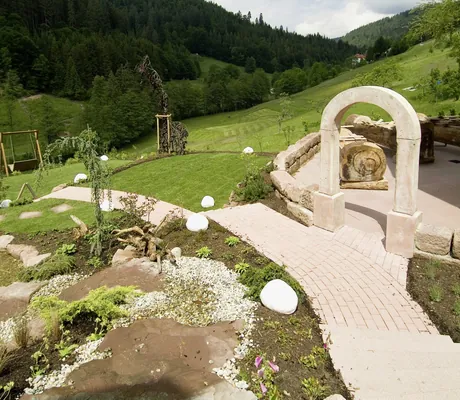 Blick in den Garten des Wellnesshotel Tanne mit Rundbogen und gepflastertem Weg