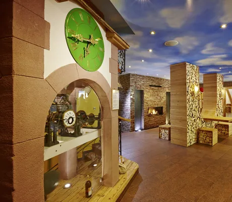 Hotelhalle im Wellnesshotel Tanne mit gestapelten Holzscheiten und grüner Uhr