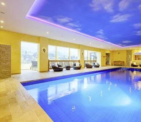 Indoorpool im Wellnesshotel Tanne mit Wolkenhimmel und Korbsesseln