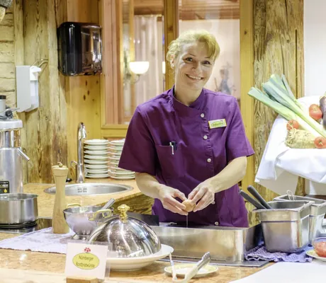 blonde Frau bereitet Eierspeise an Kochstation vor Gemüse im Wellnesshotel Tanne zu