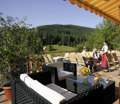 Frau in Tracht bedient Paar auf der Terrasse des Wellnesshotel Tanne