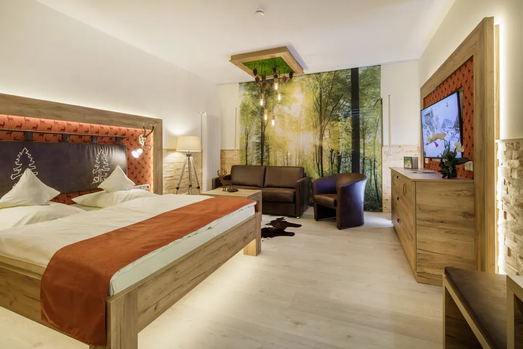 Zimmer im Wellnesshotel Tanne mit Waldtapete und orangem Bettüberwurf